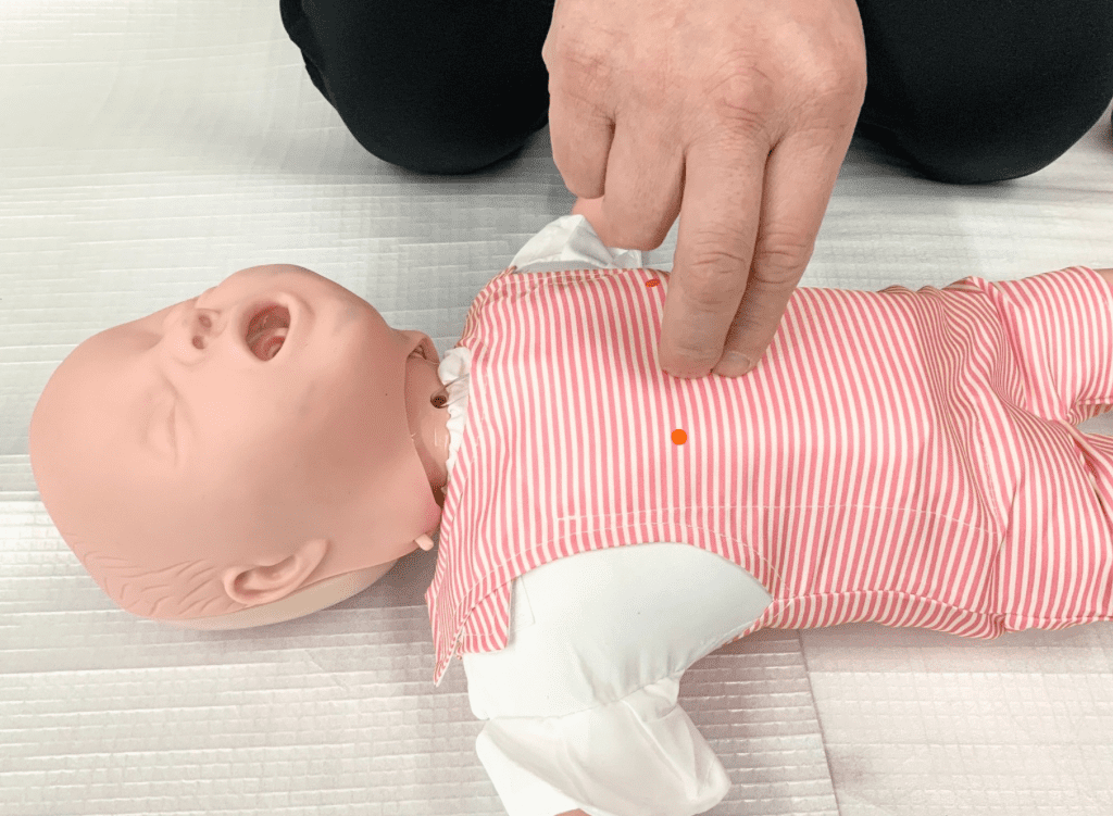 乳児の人形で心配蘇生の練習をしている