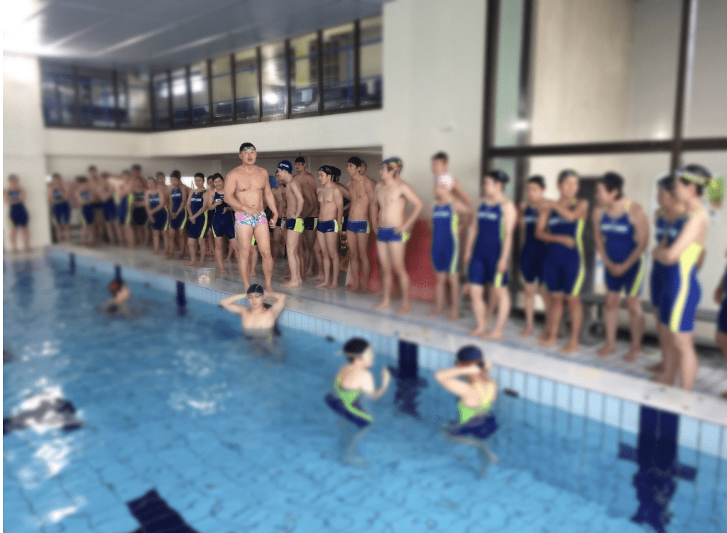 数十人の男女がプールサイドに立っている