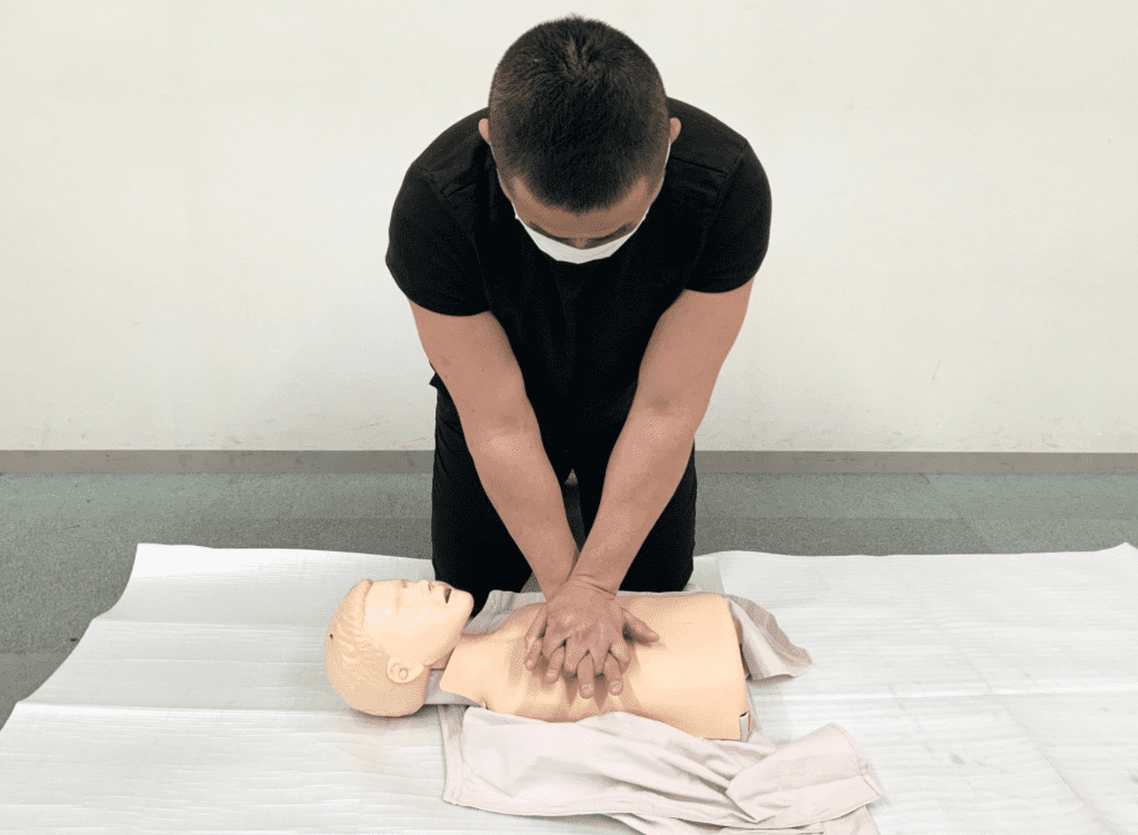 講師が心肺蘇生法の見本を教えている